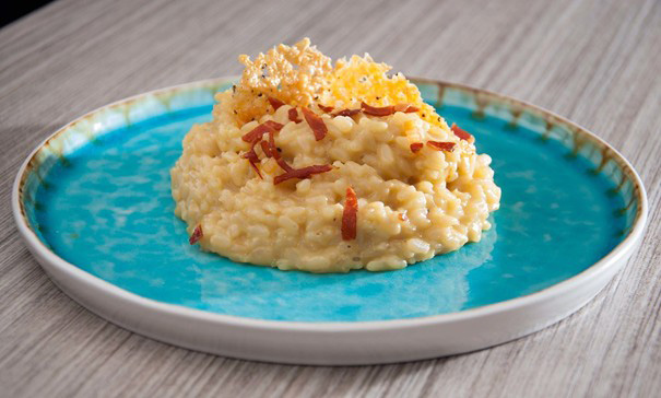 Creamy risotto served in a plate, garnished with herbs and grated cheese.